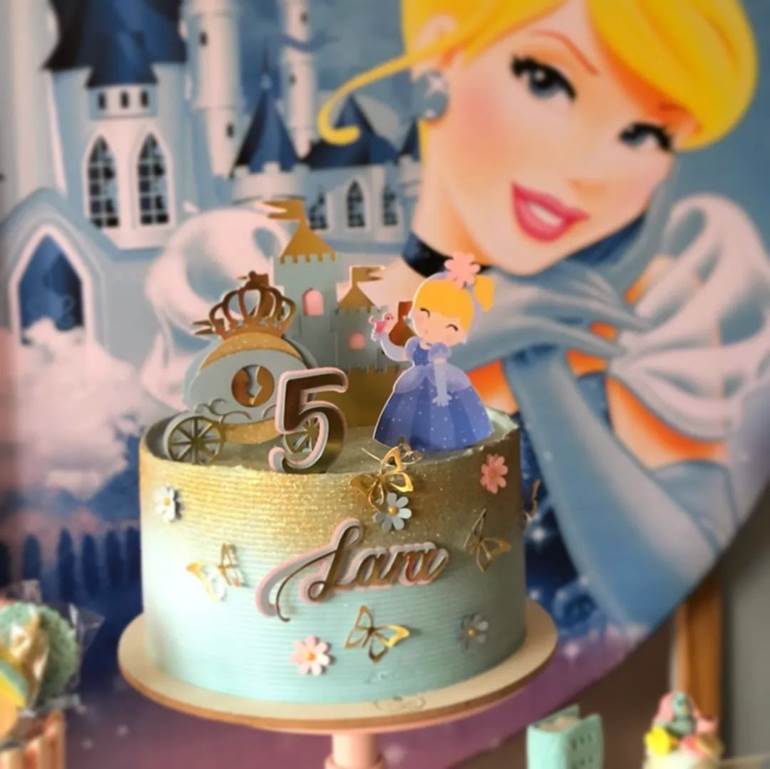 Bolo azul pastel e dourado com princesa miniatura